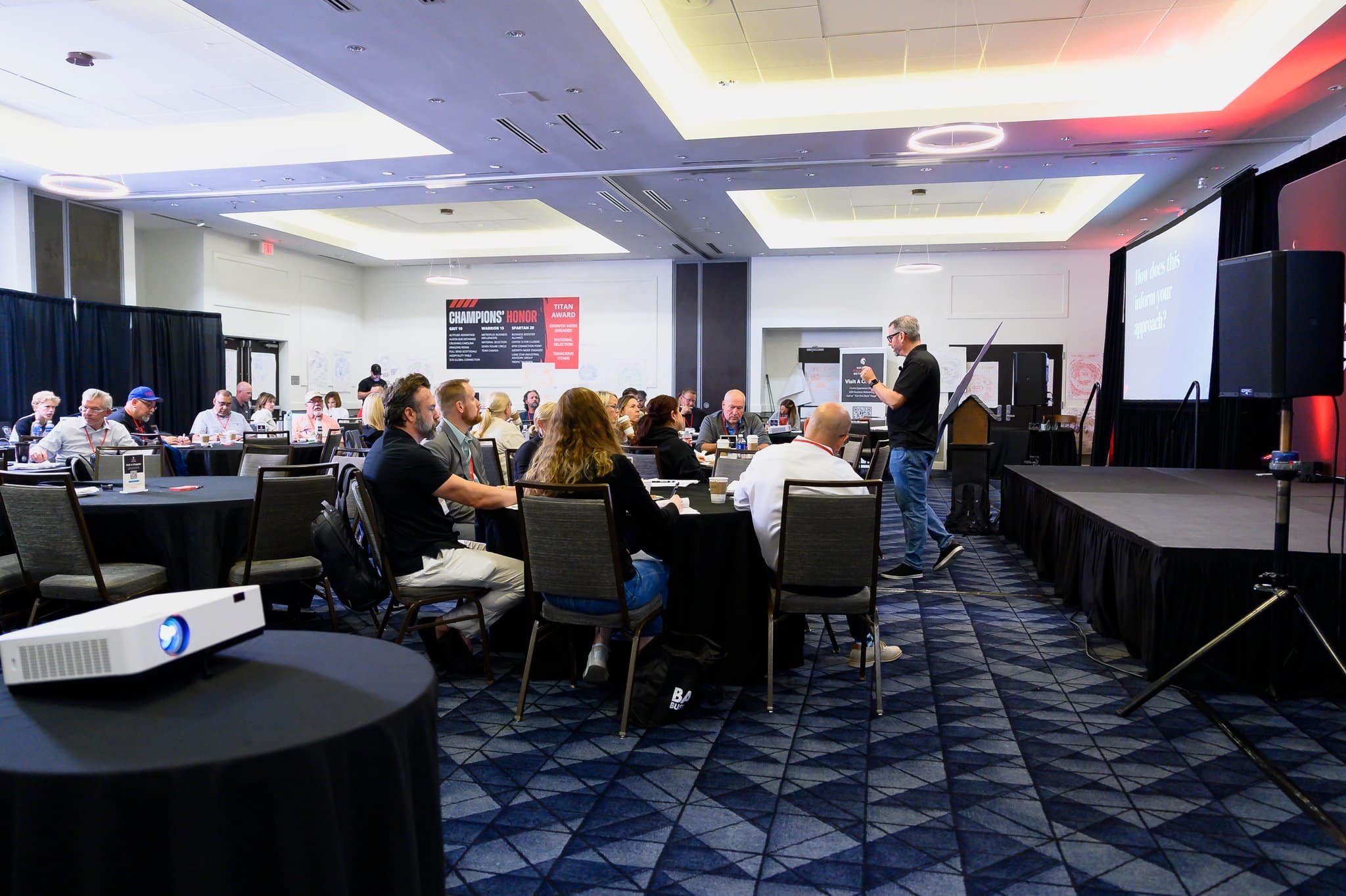 Jerry Macnamara working the room during a leadership workshop, attendees seated at round tables