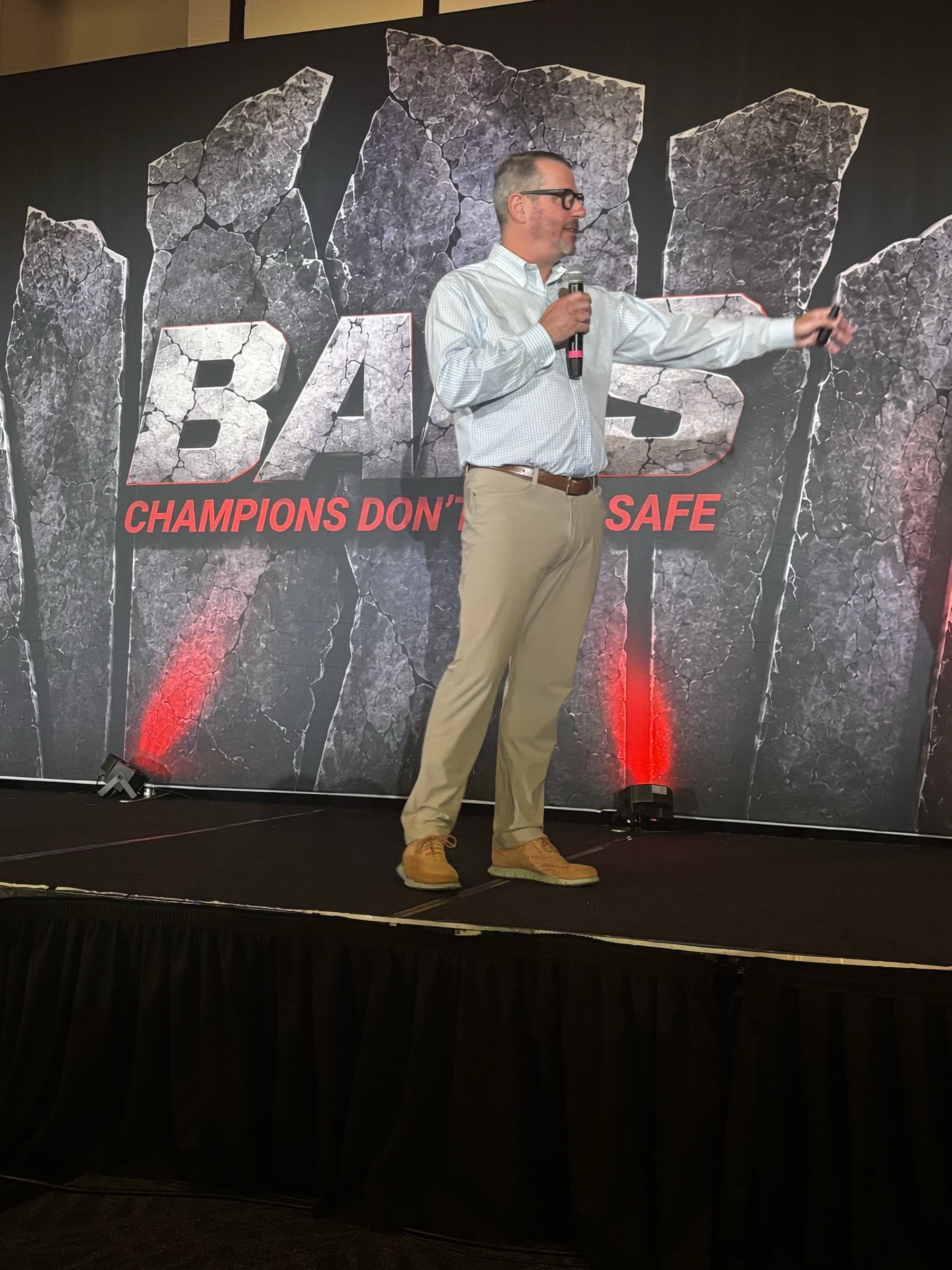 Jerry Macnamara speaking in front of the Badass Business Summit backdrop, Dallas 2026